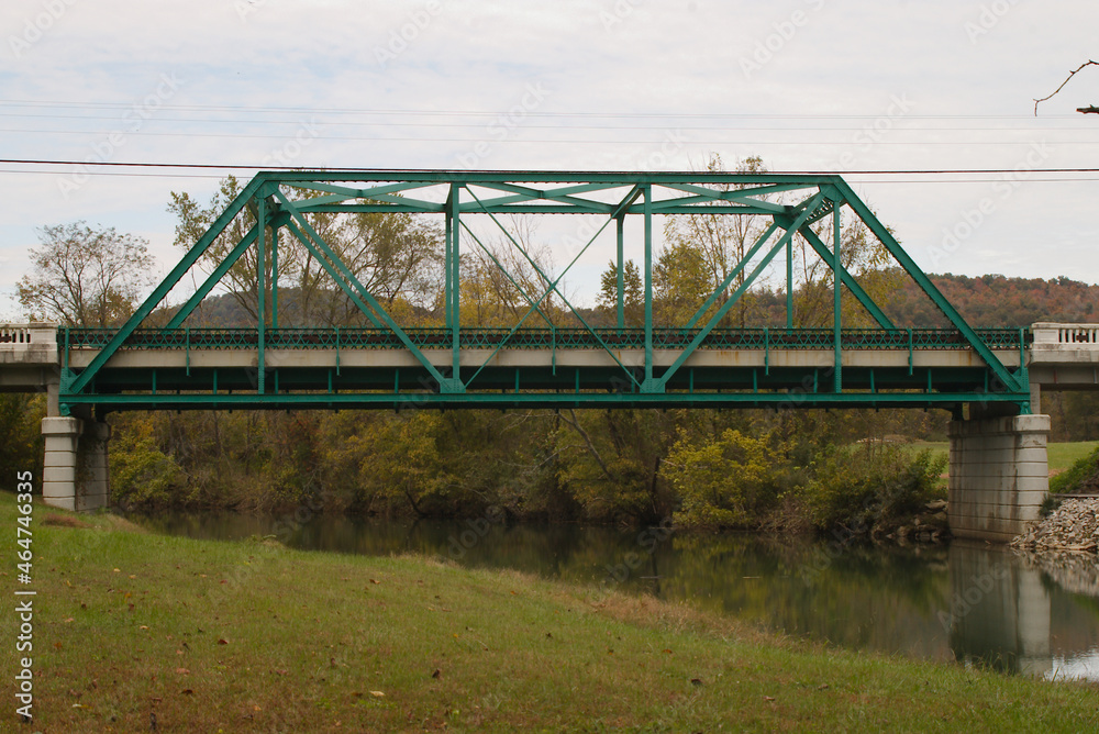 Green painted steel bridge over a stream