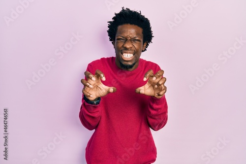 Young african american man wearing casual clothes smiling funny doing claw gesture as cat, aggressive and sexy expression