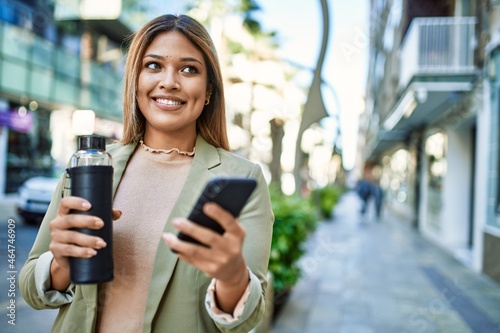 Young latin woman smiling confident using smartphone at street