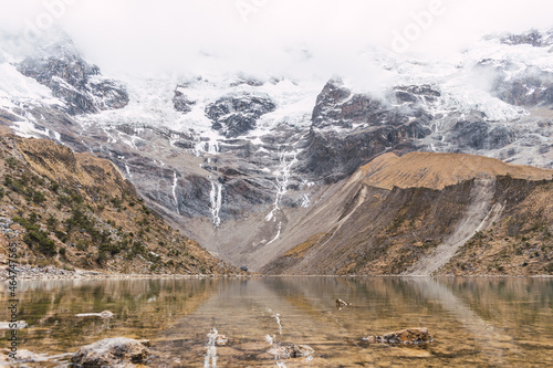 Humantay lagoon surrounded by snow-capped mountains and salcantay glaciers in the Andes mountain range of Peru on a sunny day with clouds photo