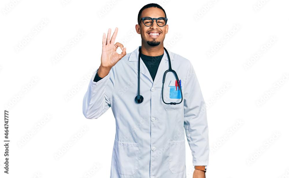 Young african american man wearing doctor uniform and stethoscope smiling positive doing ok sign with hand and fingers. successful expression. Young african american man wearing doctor uniform and stethoscope smiling positive doing ok sign with hand and fingers. successful expression.