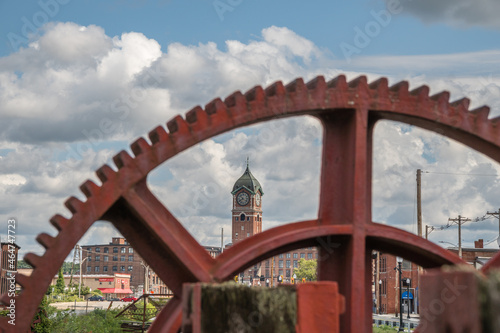 Red industrial gears with nineteenth century brick mill building in background