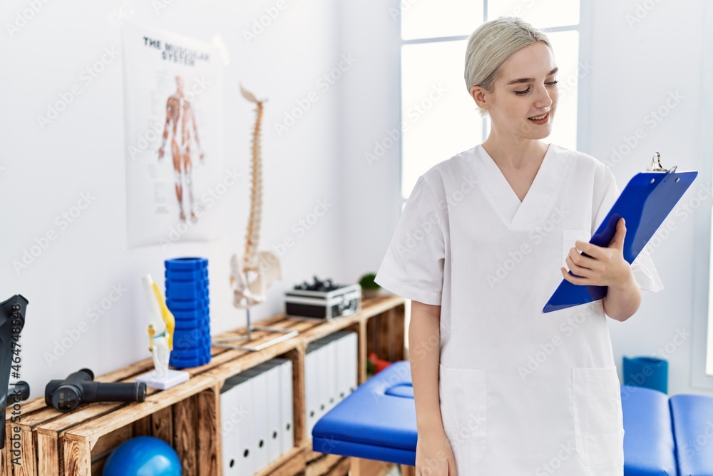 Fototapeta premium Young caucasian woman wearing physio therapist uniform working at clinic