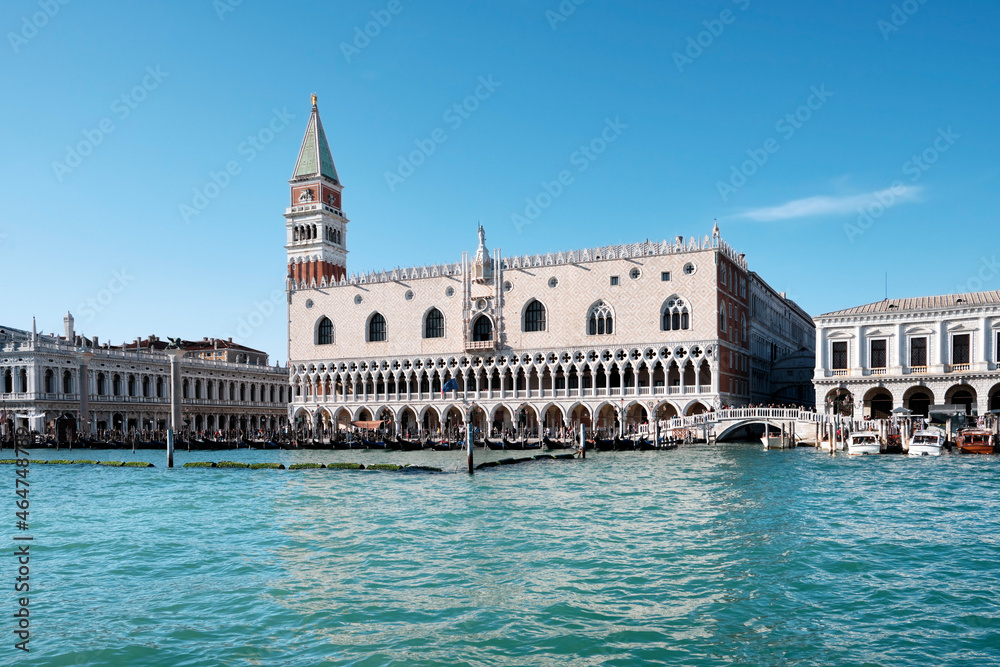 Doge's palace and St Mark's Campanile on Piazza di San Marco, Venice, Italy with reflection. View from passing vaporetto boat, with sea water of Venice Lagoon.