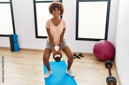 Young african american woman smiling confident training using ketlebell at sport center photo