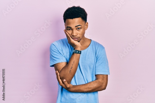 Young african american man wearing casual blue t shirt thinking looking tired and bored with depression problems with crossed arms.