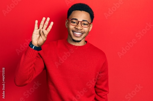 Young african american man wearing casual clothes and glasses showing and pointing up with fingers number four while smiling confident and happy. © Krakenimages.com