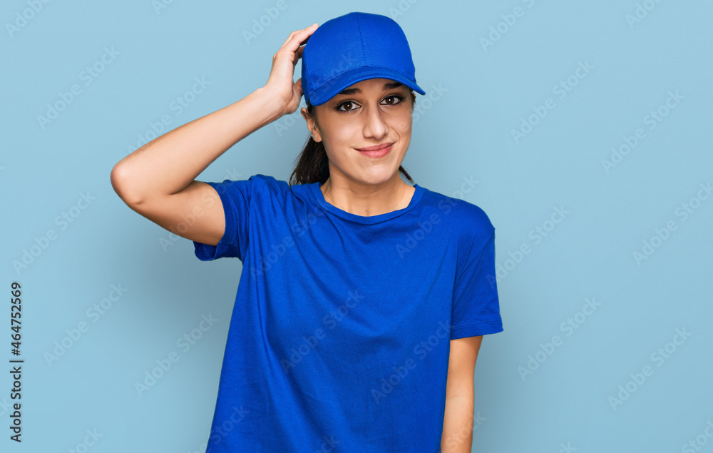 Young hispanic girl wearing delivery courier uniform confuse and wonder about question. uncertain with doubt, thinking with hand on head. pensive concept.