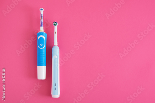 two electric blue toothbrushes on bright pink background oral hygiene concept © Natasha