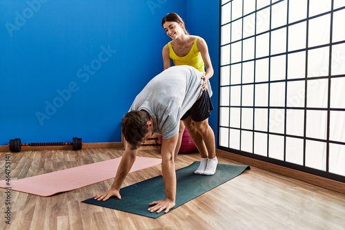 Man and woman couple smiling confident training yoga at sport center