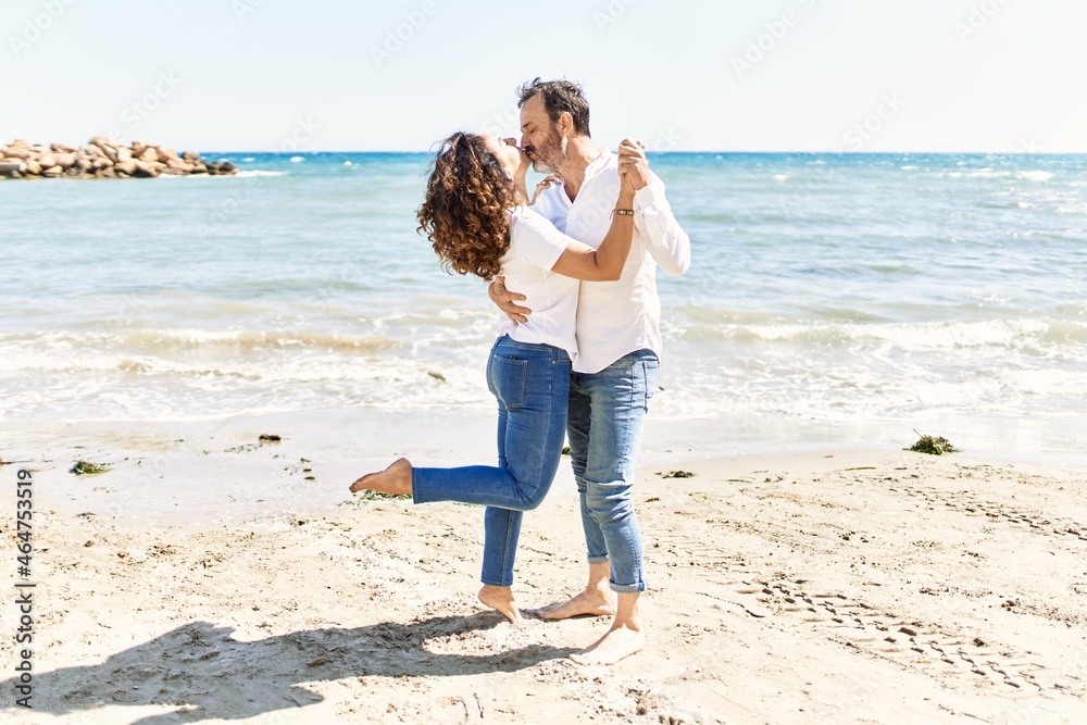 Middle age hispanic couple kissing and hugging at the beach.