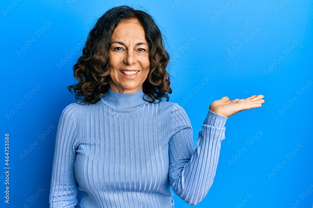 Middle age hispanic woman wearing casual clothes smiling cheerful presenting and pointing with palm of hand looking at the camera. Middle age hispanic woman wearing casual clothes smiling cheerful presenting and pointing with palm of hand looking at the camera.
