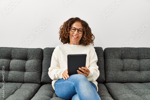 Middle age hispanic woman smiling confident using touchpad at home