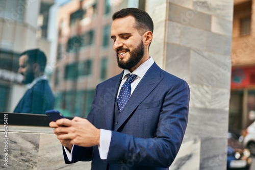 Young businessman smiling happy using smartphone at the city.