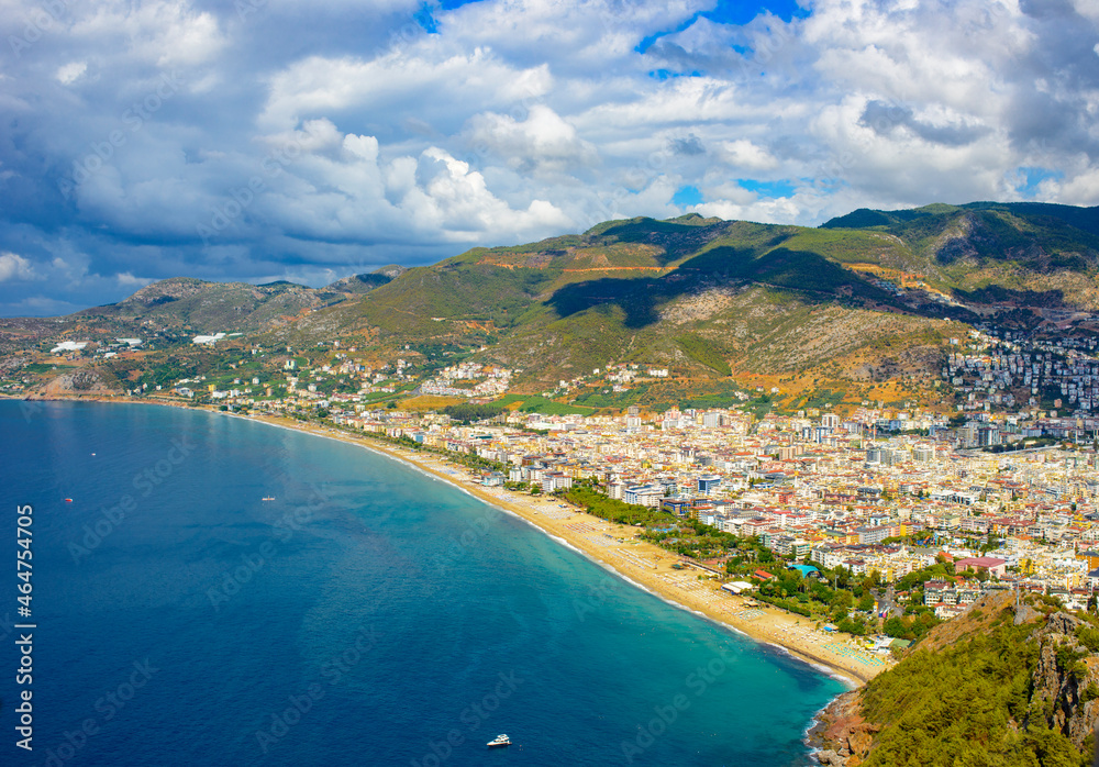 sunny view of Alanya and the port against the backdrop of mountains and clouds in autumn