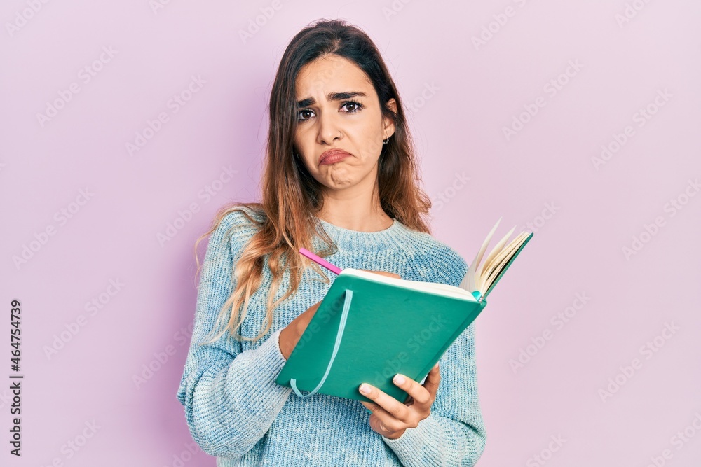 Young hispanic girl reading and writing book depressed and worry for distress, crying angry and afraid. sad expression. Young hispanic girl reading and writing book depressed and worry for distress, crying angry and afraid. sad expression.