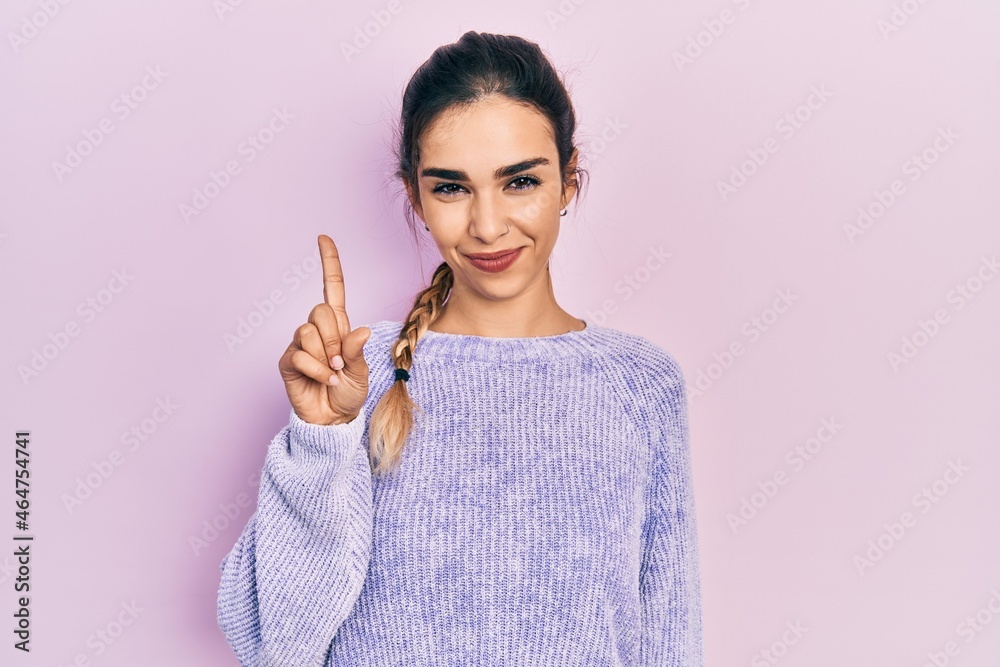 Young hispanic girl wearing casual clothes showing and pointing up with finger number one while smiling confident and happy. Young hispanic girl wearing casual clothes showing and pointing up with finger number one while smiling confident and happy.