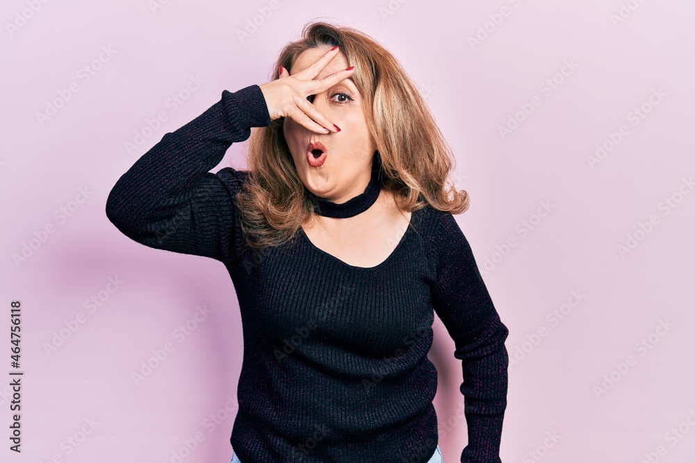 Middle age caucasian woman wearing casual clothes peeking in shock covering face and eyes with hand, looking through fingers with embarrassed expression. Middle age caucasian woman wearing casual clothes peeking in shock covering face and eyes with hand, looking through fingers with embarrassed expression.