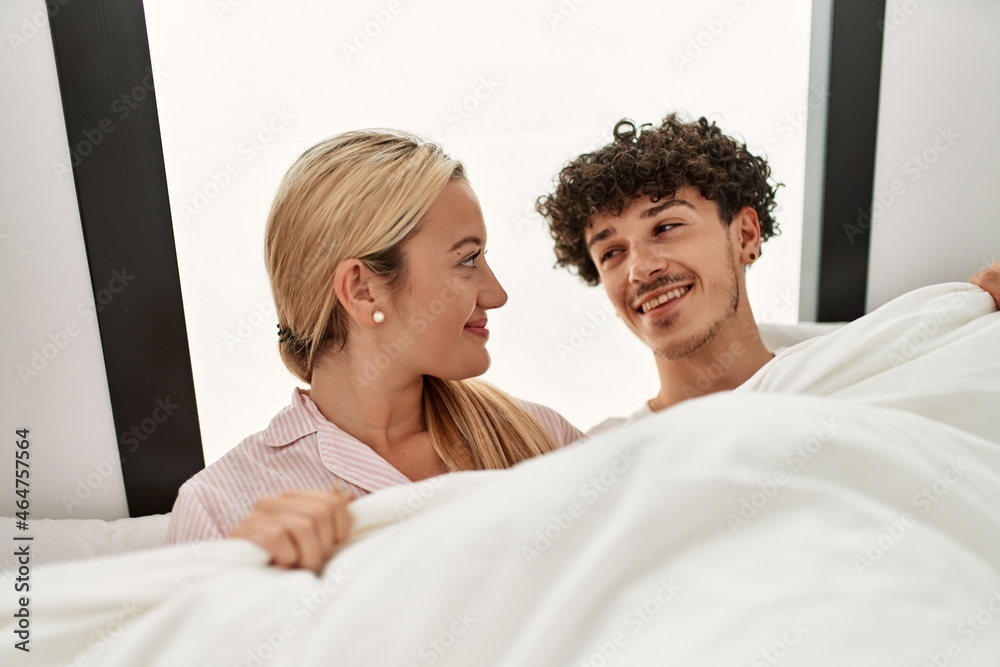 Young beautiful couple lying in bed and covering with blanket at home. Young beautiful couple lying in bed and covering with blanket at home.
