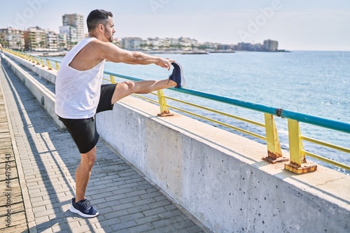 Fototapeta Naklejka Na Ścianę i Meble -  Hispanic man stretching legs after working out outdoors on a sunny day