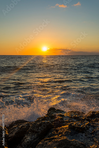 romantic sunset on the mediterranean coast with bursts of sea waves in the sun