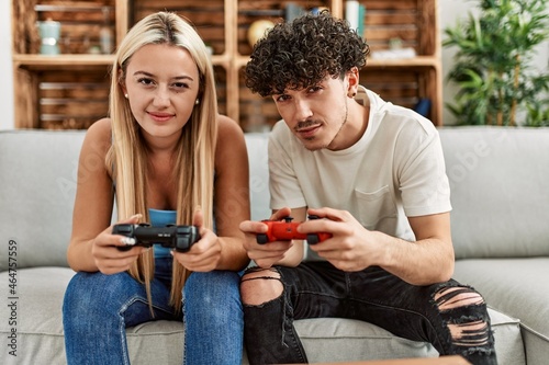 Young couple smiling happy playing video game at home.