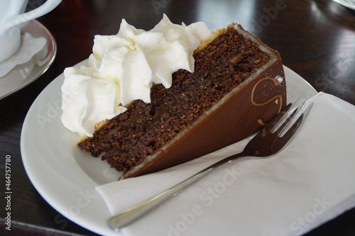 a piece of delicious luxury chocolate Vienna cake or Sachertorte or Sacher-Torte or Sacher Torte with whipped cream and a little fork on a plate, Vienna, Austria