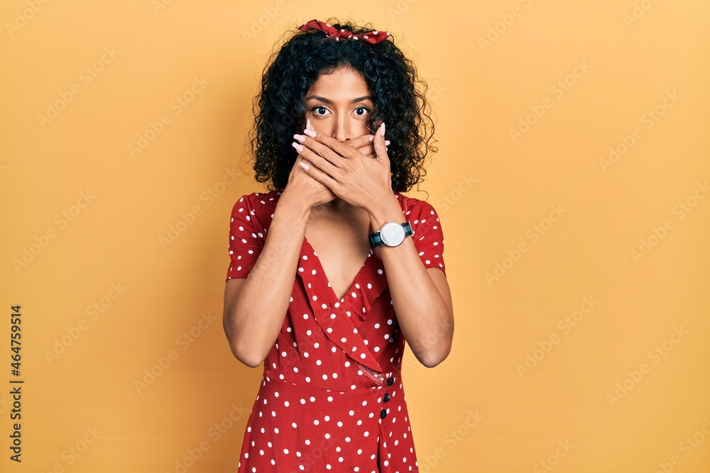 Young latin girl wearing summer dress shocked covering mouth with hands for mistake. secret concept. Young latin girl wearing summer dress shocked covering mouth with hands for mistake. secret concept.