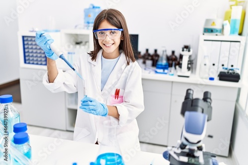 Young hispanic girl working using pipette at laboratory