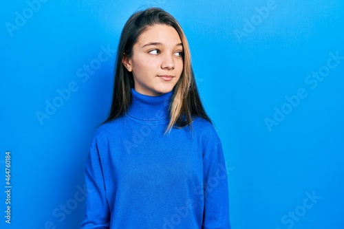 Young brunette girl wearing turtleneck sweater smiling looking to the side and staring away thinking.