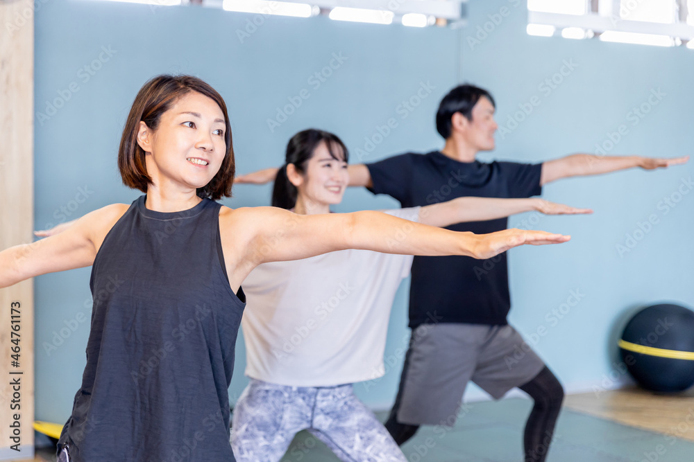 Naklejka premium スポーツジムでヨガをする男女(戦士のポーズ)