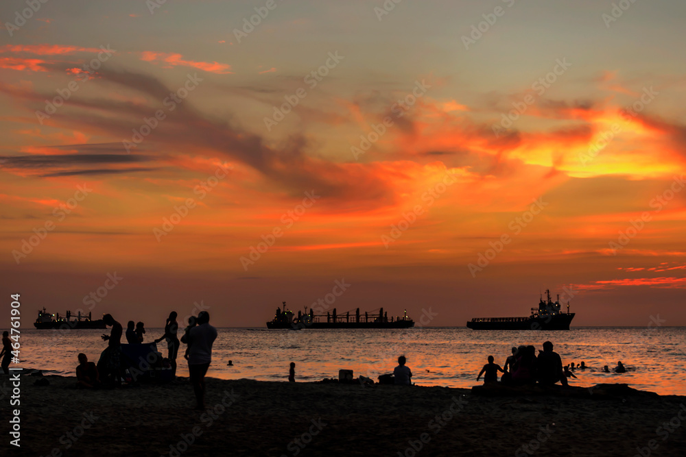 Silhouettes of a group of people on a beach on a colorful sunset