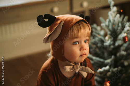 Toddler baby boy in rudolph reindeer costumes decorating Christmas tree