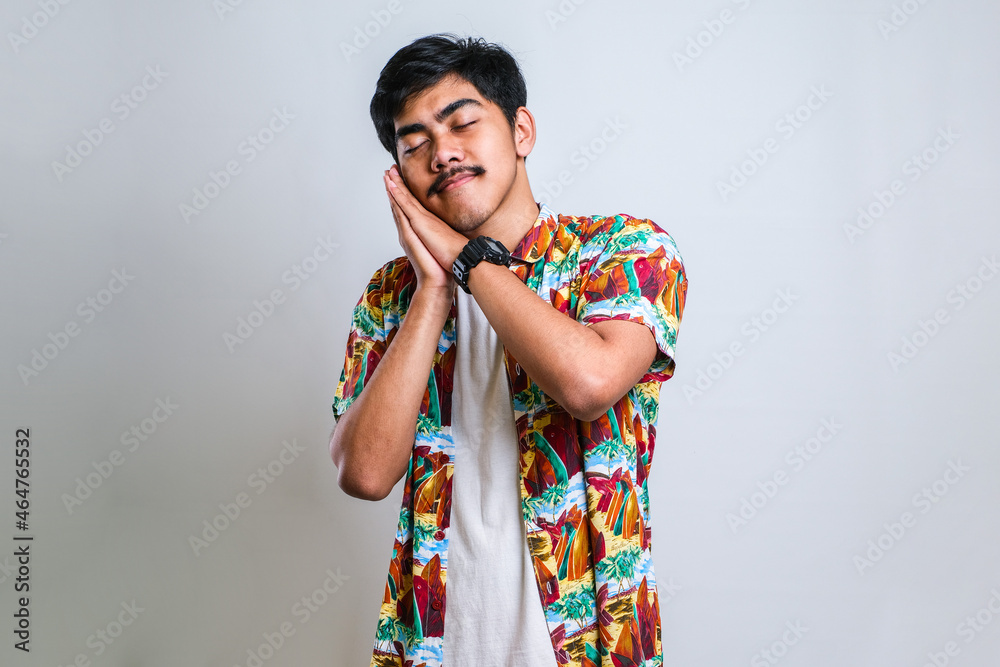 Asian man sleeping tired dreaming and posing with hands together while smiling with closed eyes Asian man sleeping tired dreaming and posing with hands together while smiling with closed eyes