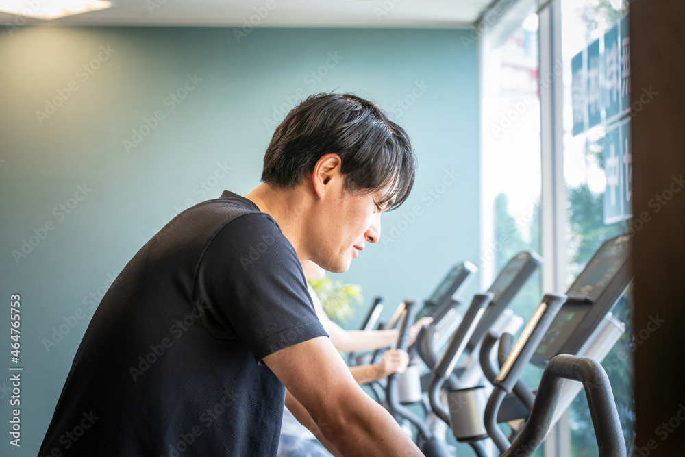 Fototapeta premium エアロバイクで運動する男性
