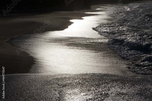 Sunset sunlight reflecting on the wave-wet beach sand