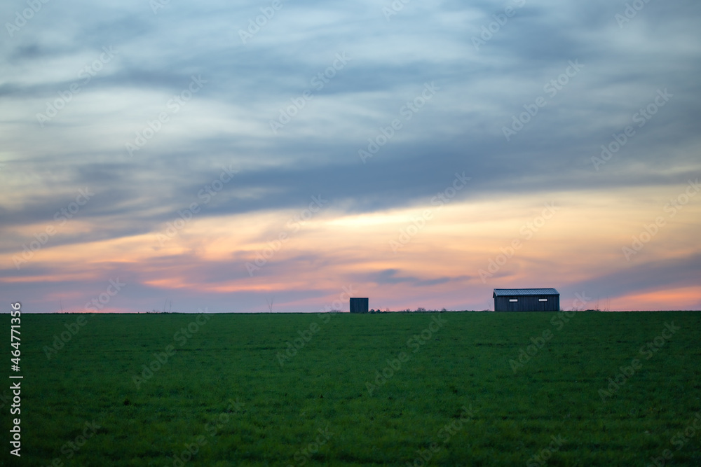Fototapeta premium Coucher du soleil coloré sur une maison isolée dans un champ