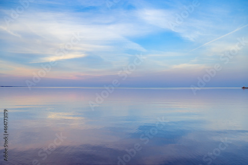Sky background on sunset, colorful clouds. Nature abstract composition with reflections on sea water. Nature environment. © yrabota