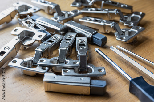 A pile of soft close cabinet door hinges and screwdrivers