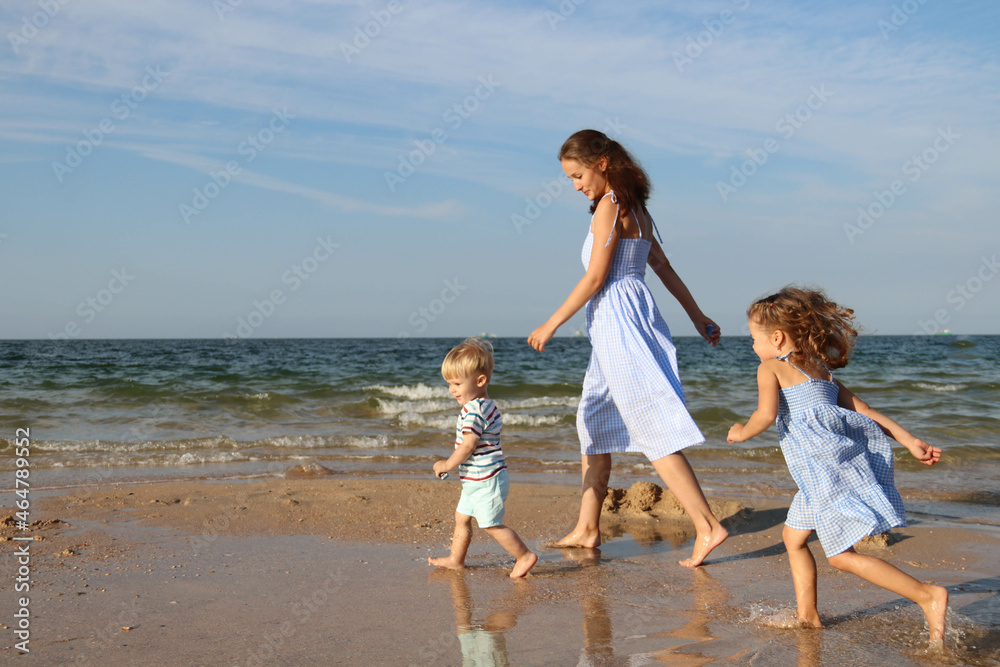 Happy harmonious family outdoors concept. Mother and children spend time together on vacation at the seas