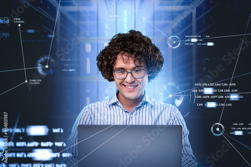 Smiling programmer portrait in glasses, sitting in front of lapt photo