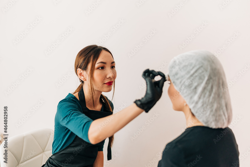 Permanent makup on face, woman having eyelid tattoo in beauty salon