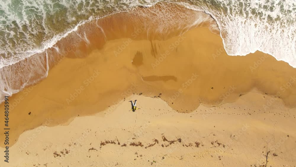 A man in clothes lies on a deserted beach next to the rolling waves of the sea. View from above. Relaxing on the beach alone. Meditation on the beach. A man in clothes lies on a deserted beach next to the rolling waves of the sea. View from above. Relaxing on the beach alone. Meditation on the beach.