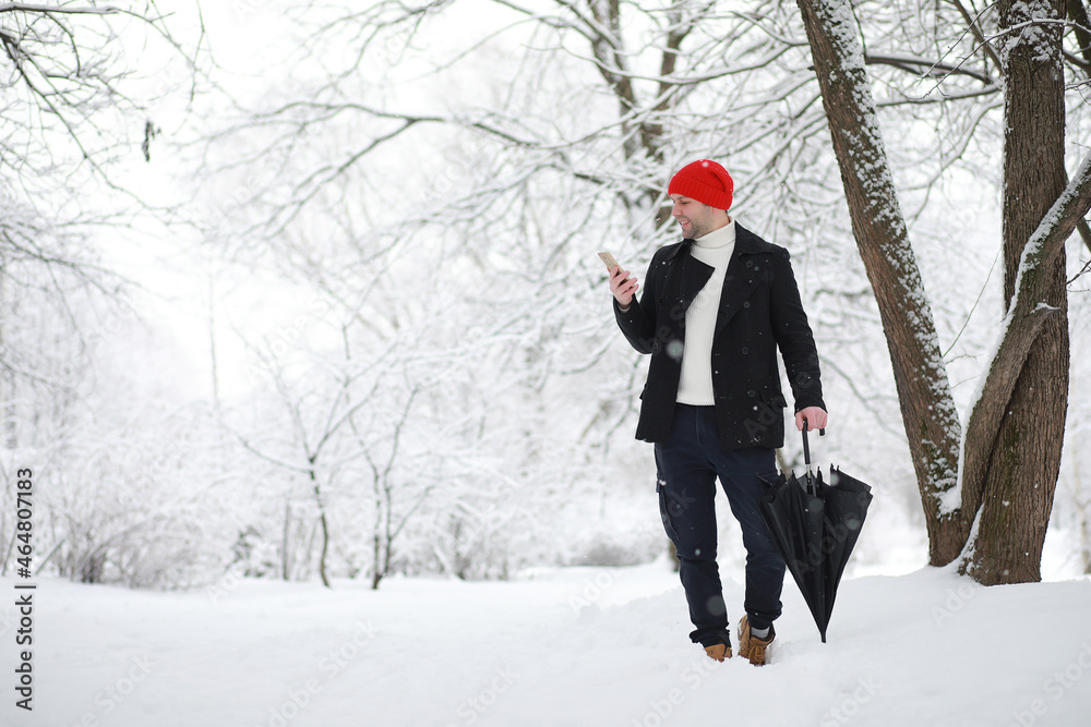 A man on a walk in the park. Young man with in the winter snowfall. A man on a walk in the park. Young man with in the winter snowfall.