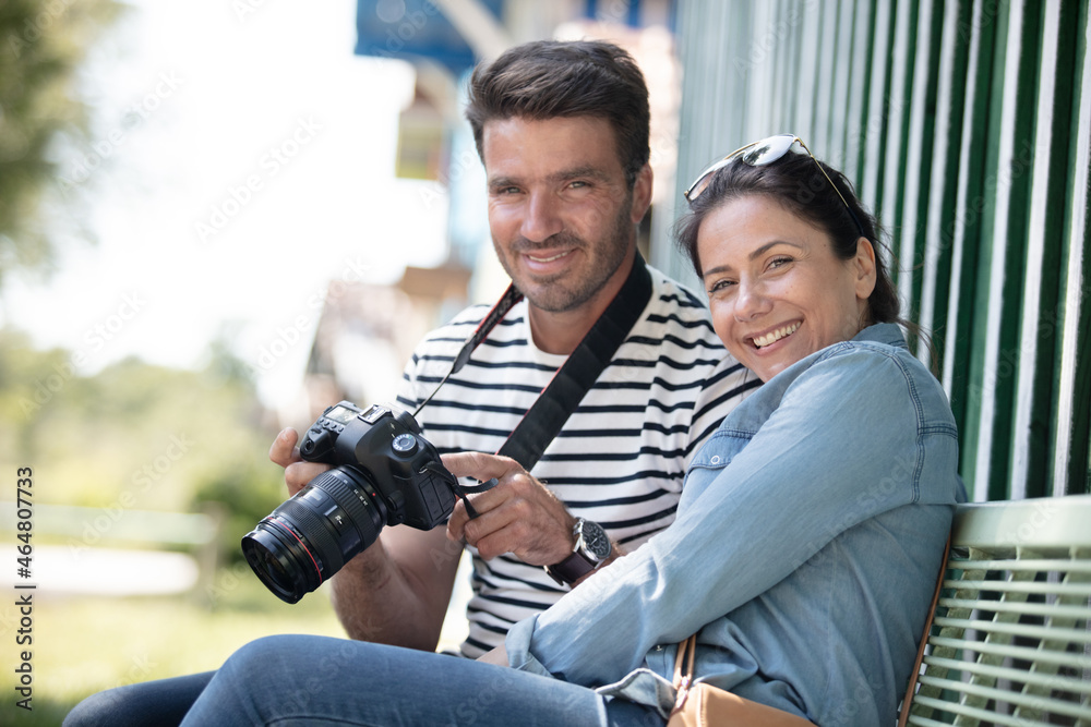couple of tourists reviewing photos in a dslr camera s couple of tourists reviewing photos in a dslr camera s