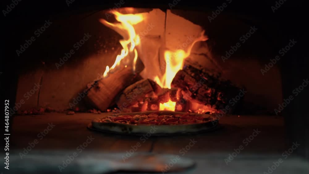 pizza is baked in an open firewood oven. Burning firewood on the background. Traditional hot pizza margarita pizza is baked in an open firewood oven. Burning firewood on the background. Traditional hot pizza margarita