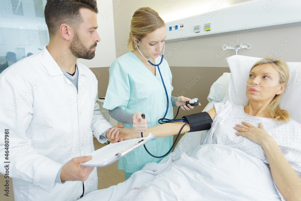 Obraz premium female doctor checking blood pressure of senior woman in bed