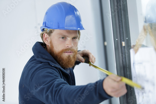 man is measuring a window