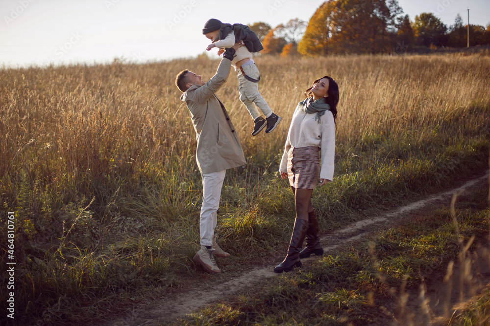 family of three with a boy child mom and dad throws up on a field family of three with a boy child mom and dad throws up on a field