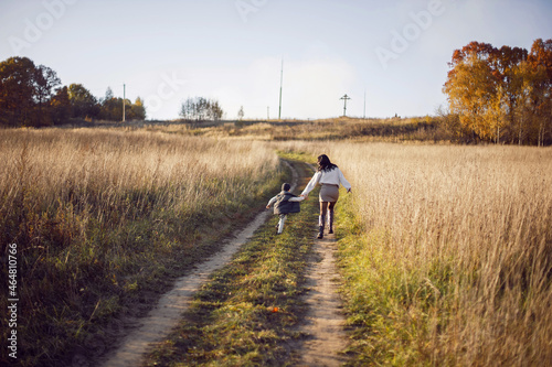 mother and her son are run in a field with dry grass at sunset